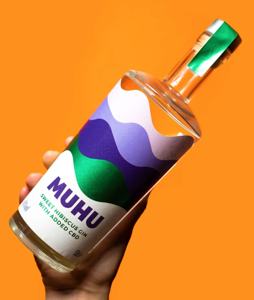 A hand holding a bottle of Muhu CBD gin against a colourful background