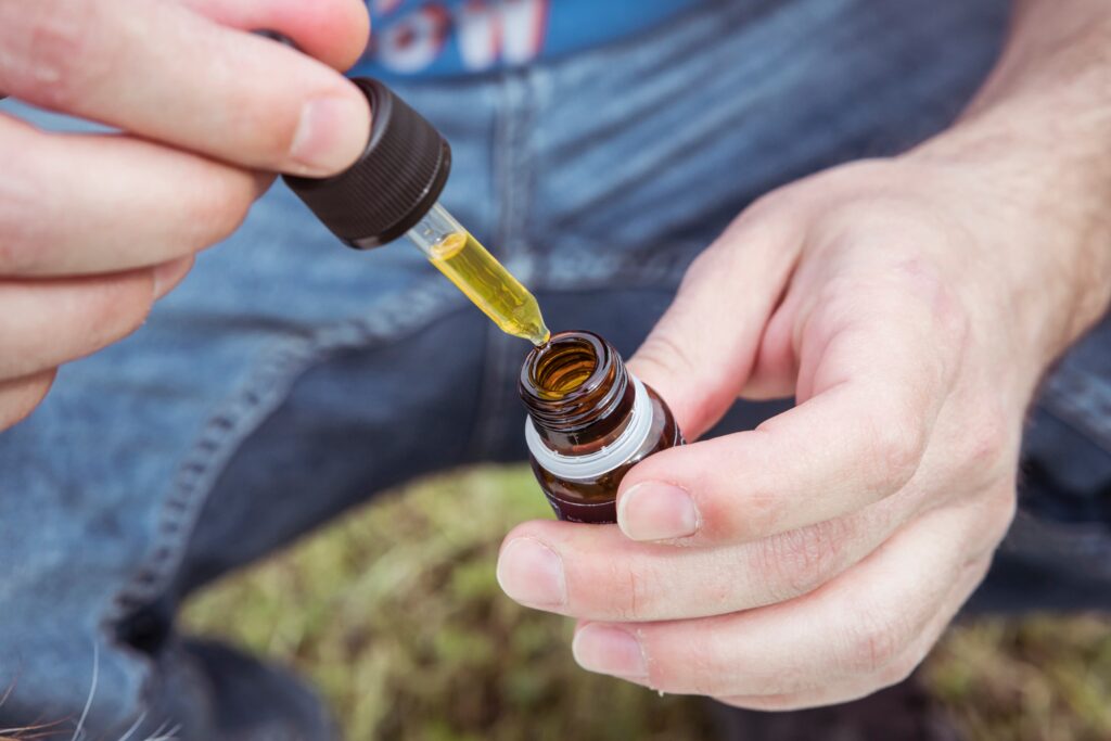 Hands opening a CBD tincture bottle
