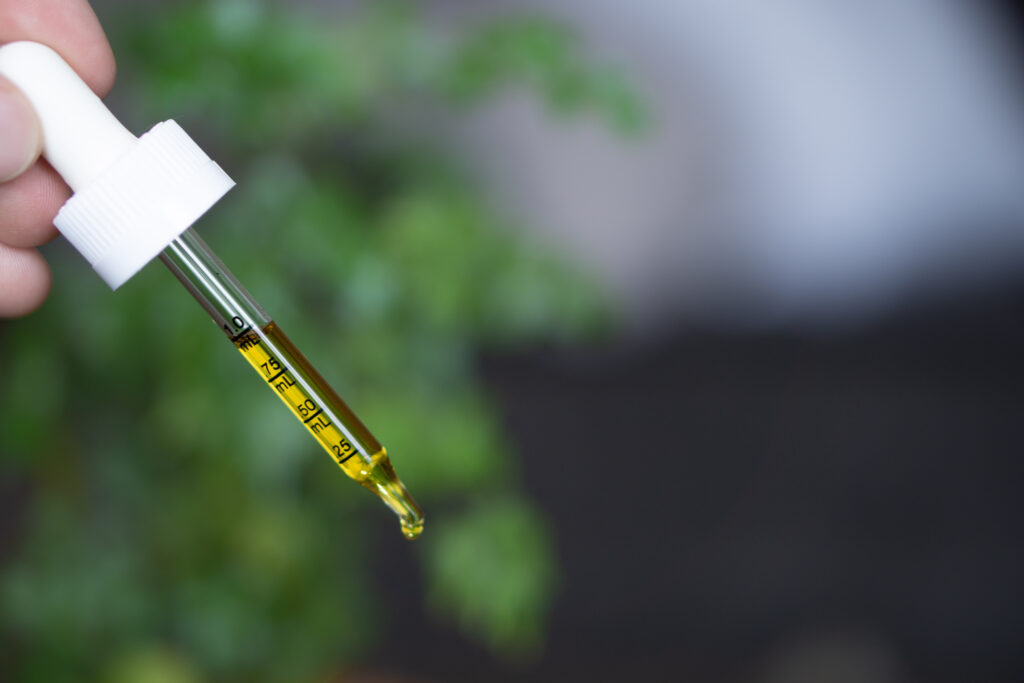 A tincture dropper with CBD oil pouring a drop into the air