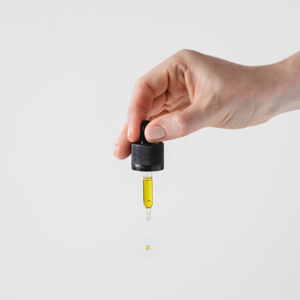 A white hand emerges from the right hand side of the page holding a cannabis oil dropper whose usage is to treat medical condition.