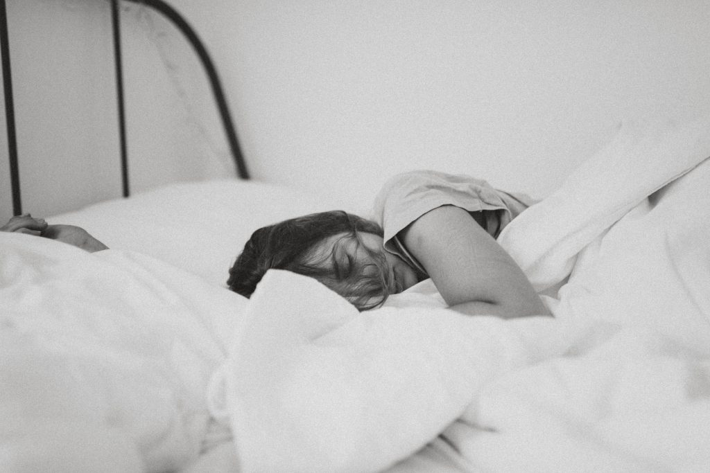 A black and white image of a woman in white bedding.