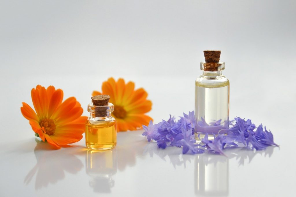 Two small bottles of cbn oil are on a white background surrounded by flowers