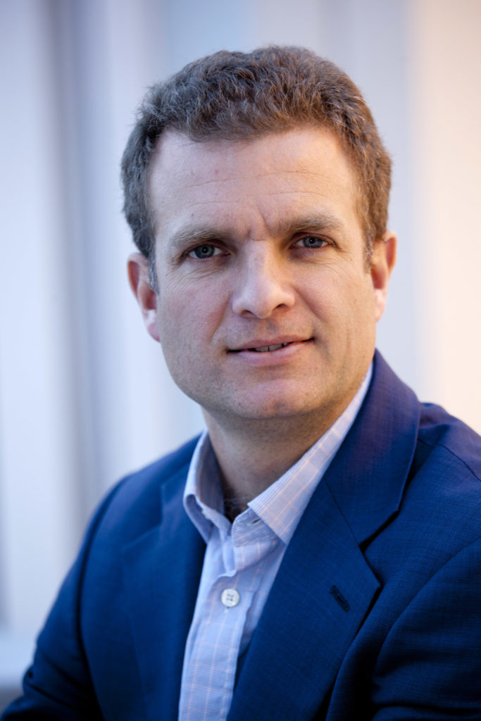 A gentleman dressed in a blue suit poses for a photograph