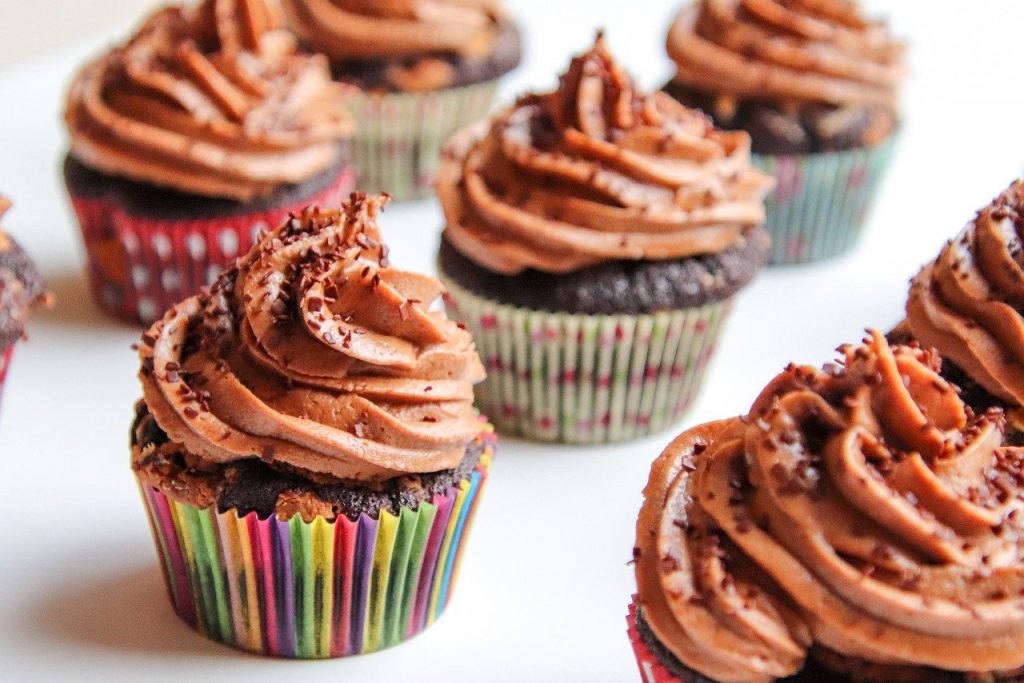 Chocolate cupcakes with frosting and sprinkles in multicoloured casing. 