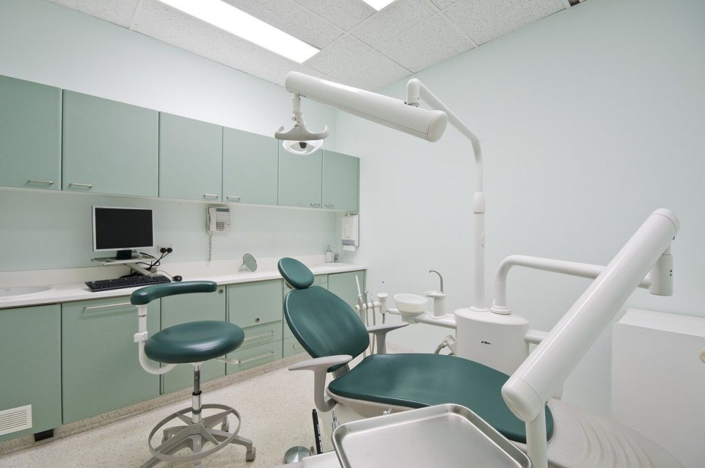 A green and white dentist chair with equipment surrounding it