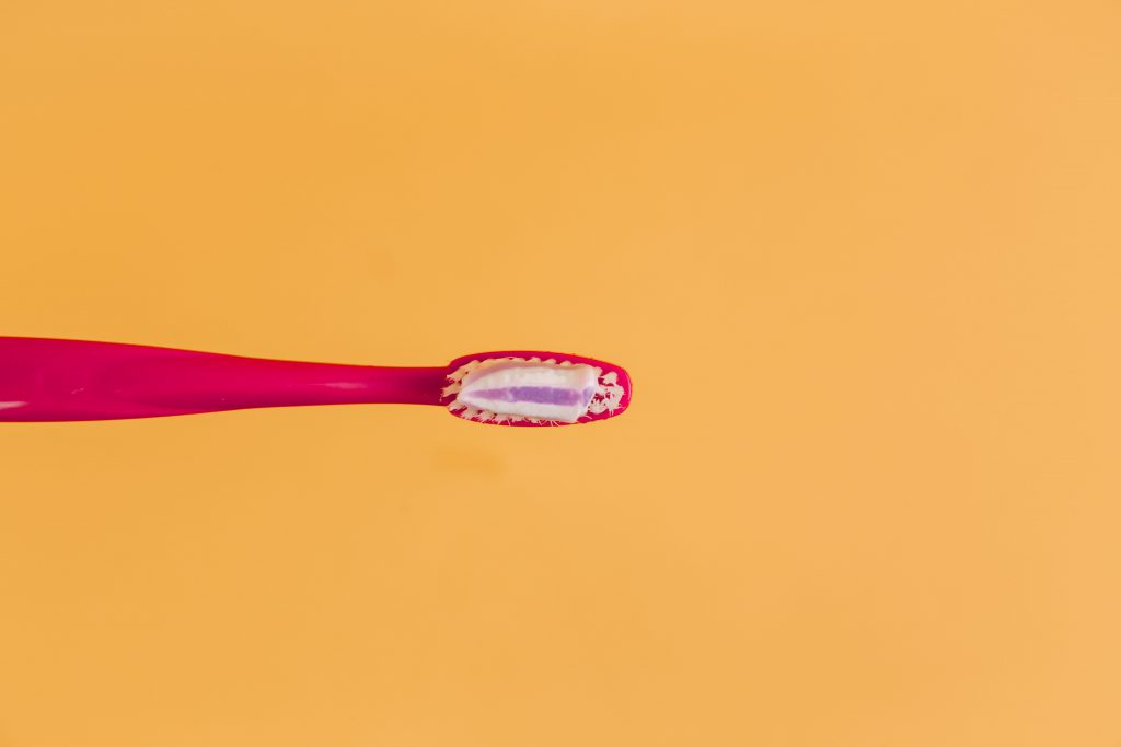 A red toothbrush against an orange background