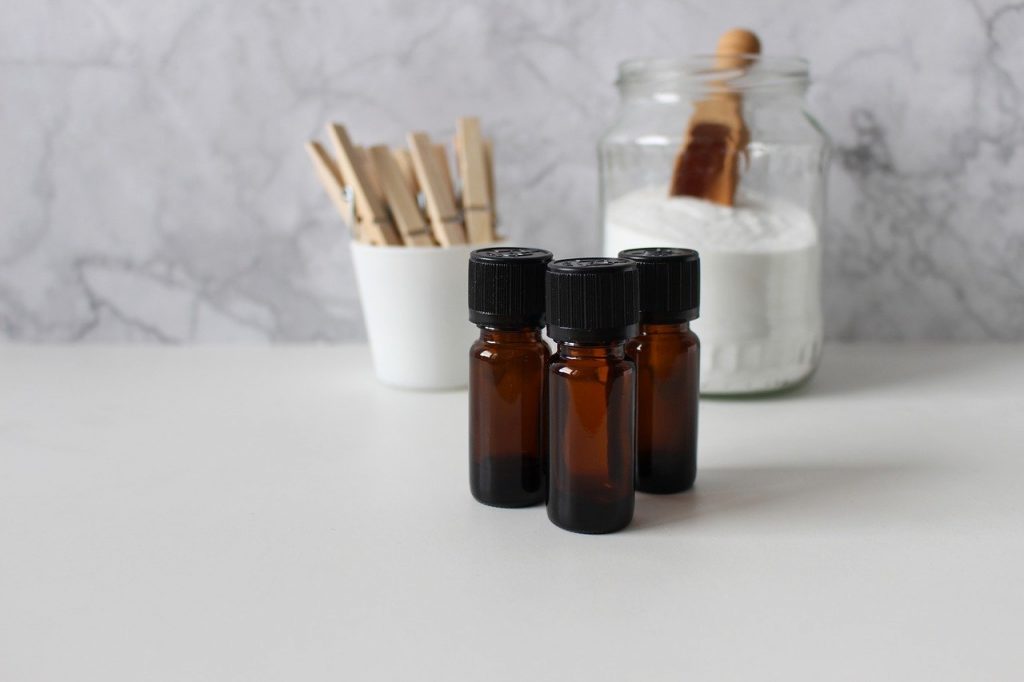 Three brown bottles of CBD oil on the white counter top in a kitchen with a container of flour in the background.